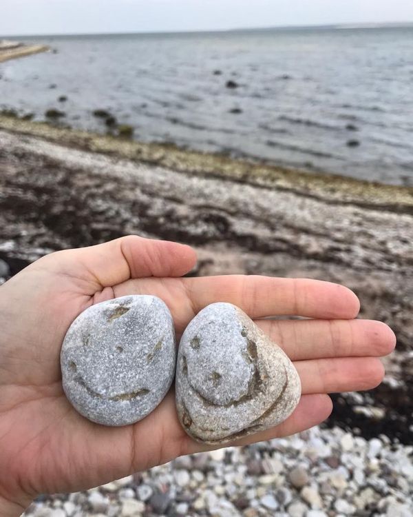 Mererannas hoiab käsi kahte rõõmsa näoga kivi oma peos