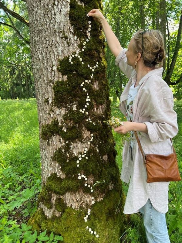 Looduskunstiterapeut kaunistab sammaldunud puu tüve pisikeste valgete lilledega.
